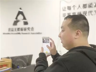 图:来自《科技日报》报道配图 视障者正使用QQ空间图片描述功能